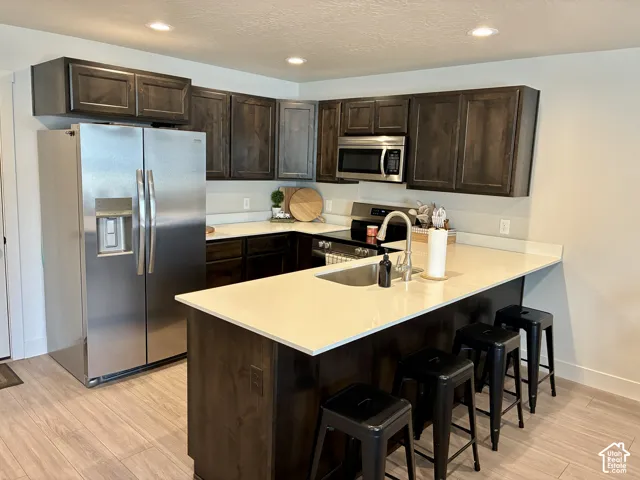 Stainless steel refrigerator (included), built-in microwave, dark wood-finish cabinetry, light-toned countertops, and wood-finish flooring