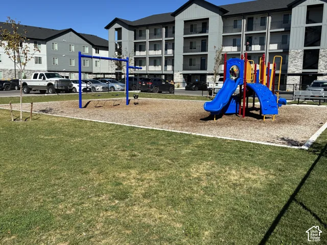 Community playground featuring a swing set and slide structure and fully fenced for safety