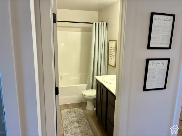 Hallway Bathroom featuring a tub/shower combination, wood-finish flooring, and a vanity with an integrated sink.