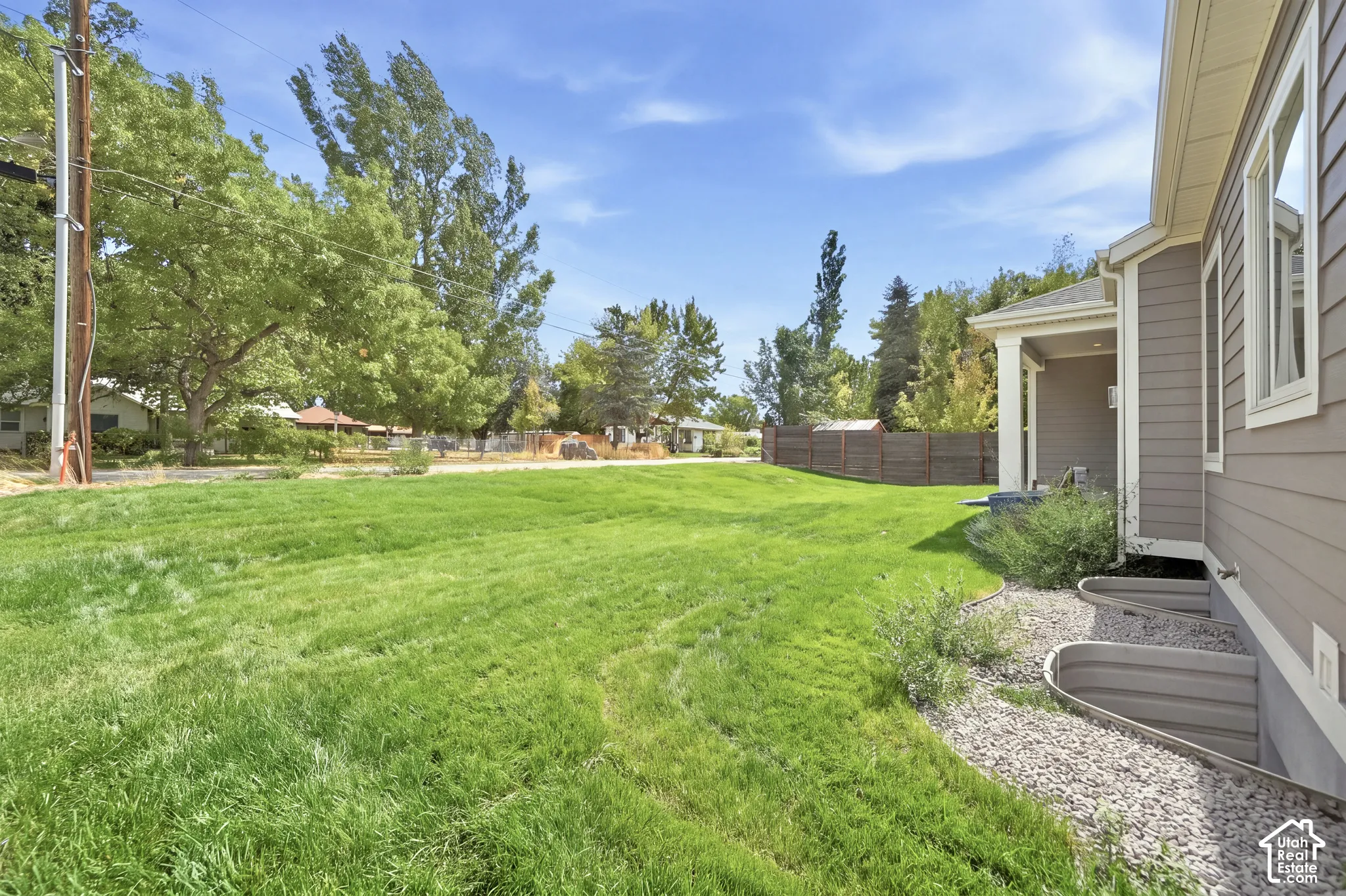 Expansive lawn area with a solid panel fence and mature trees