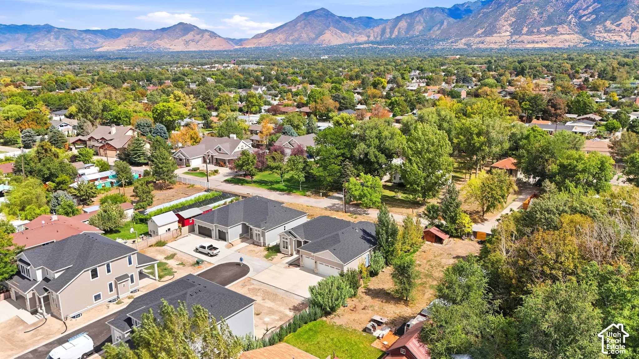 Panoramic mountain backdrop, mature tree-lined streets, residential neighborhood setting, modern rooflines, and ample green space