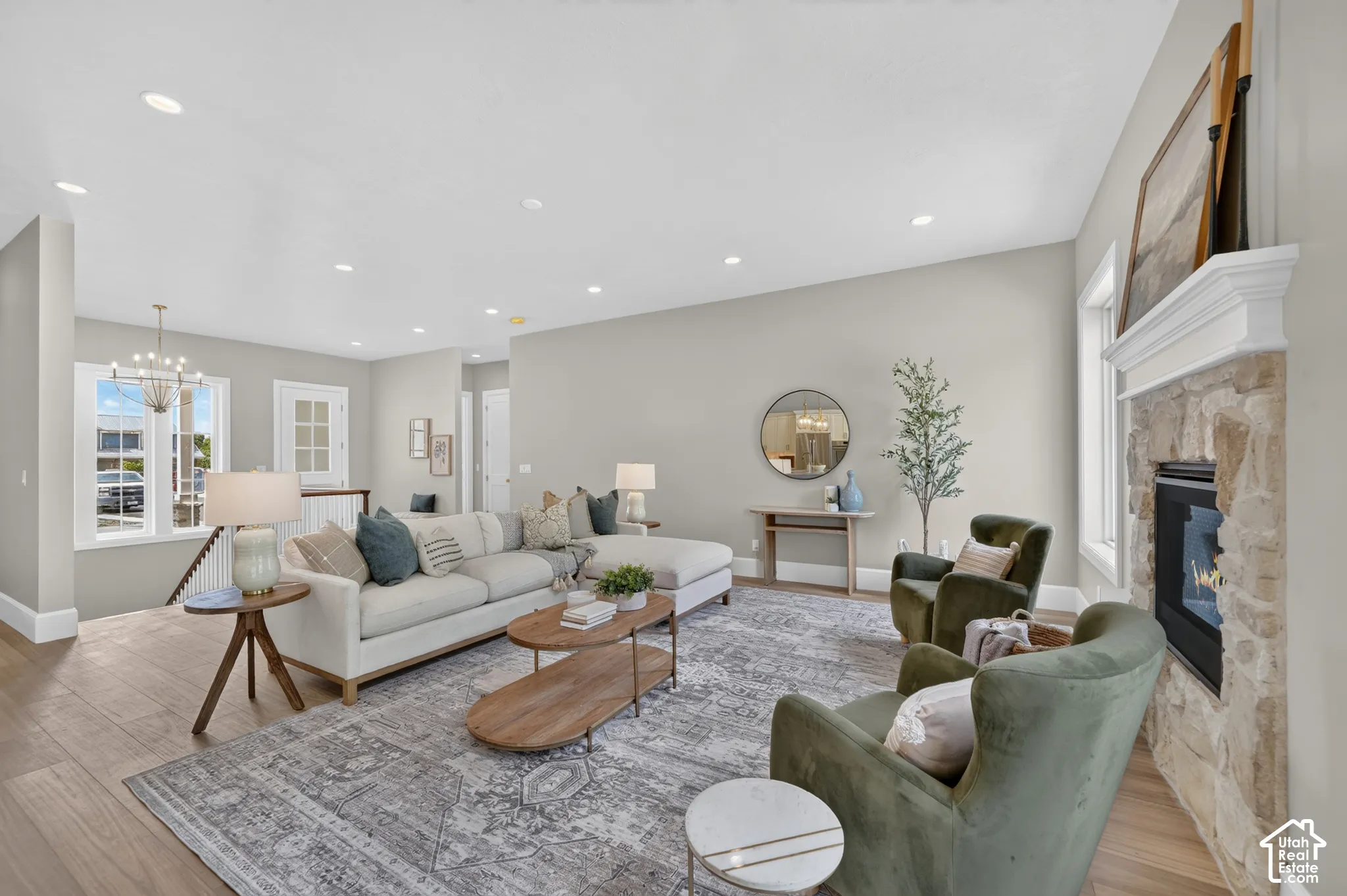 Spacious living area featuring wood-finish flooring, a stone-clad fireplace with a white mantel, and recessed lighting