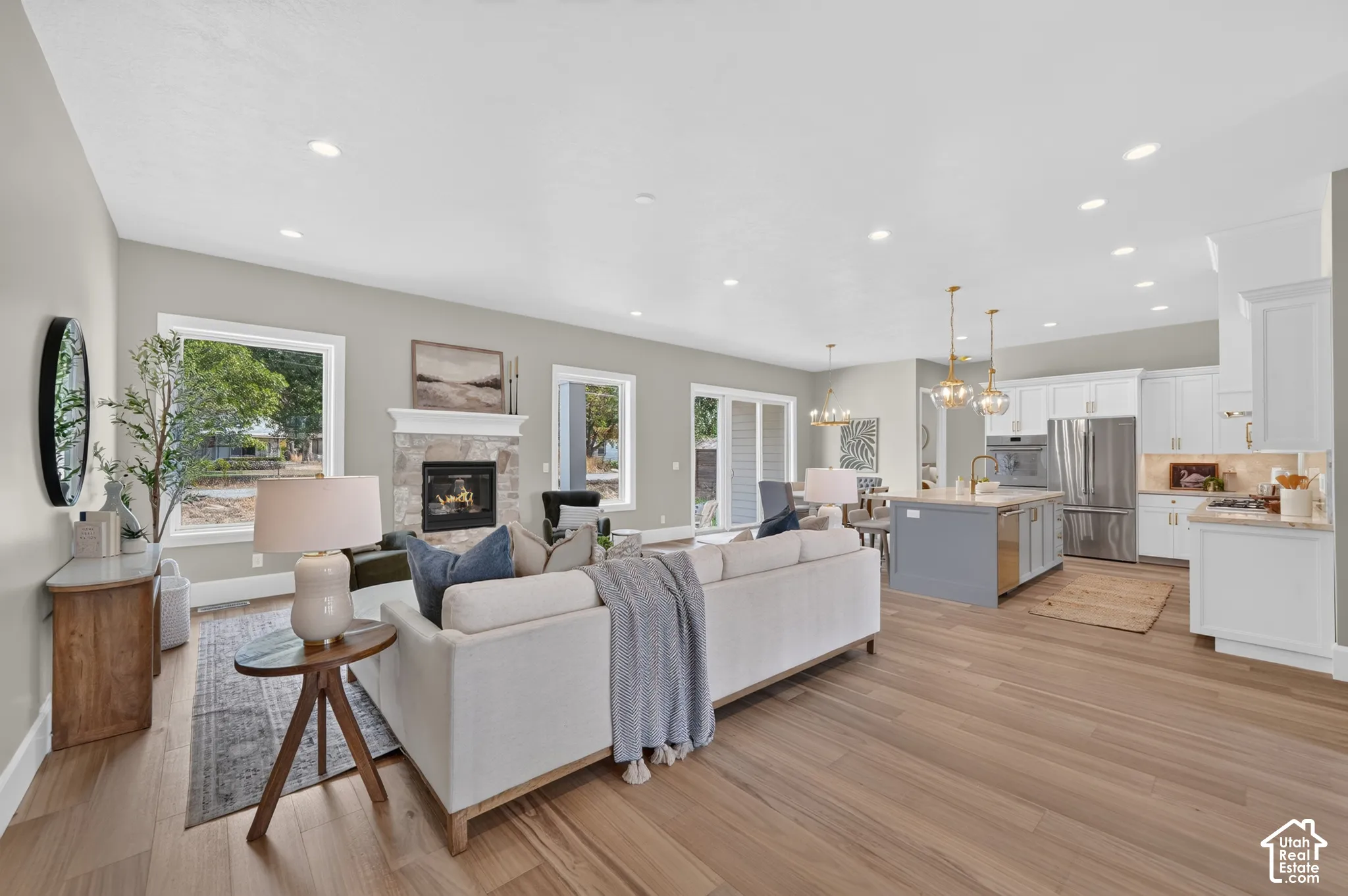 Expansive common area featuring wood-finish flooring, a stone-clad fireplace, and recessed lighting