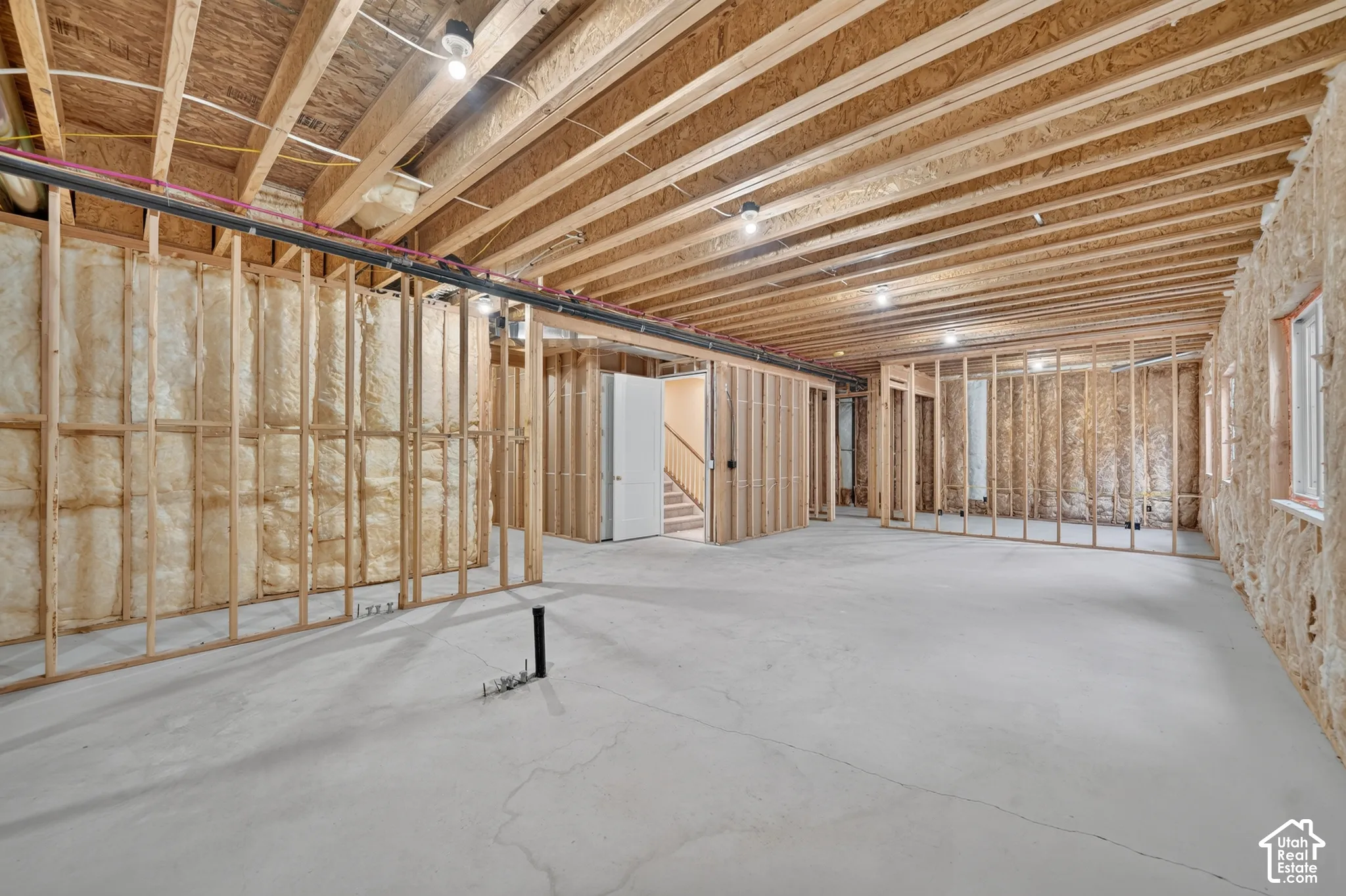 Unfinished basement with concrete flooring, exposed wood joists, and framed interior walls