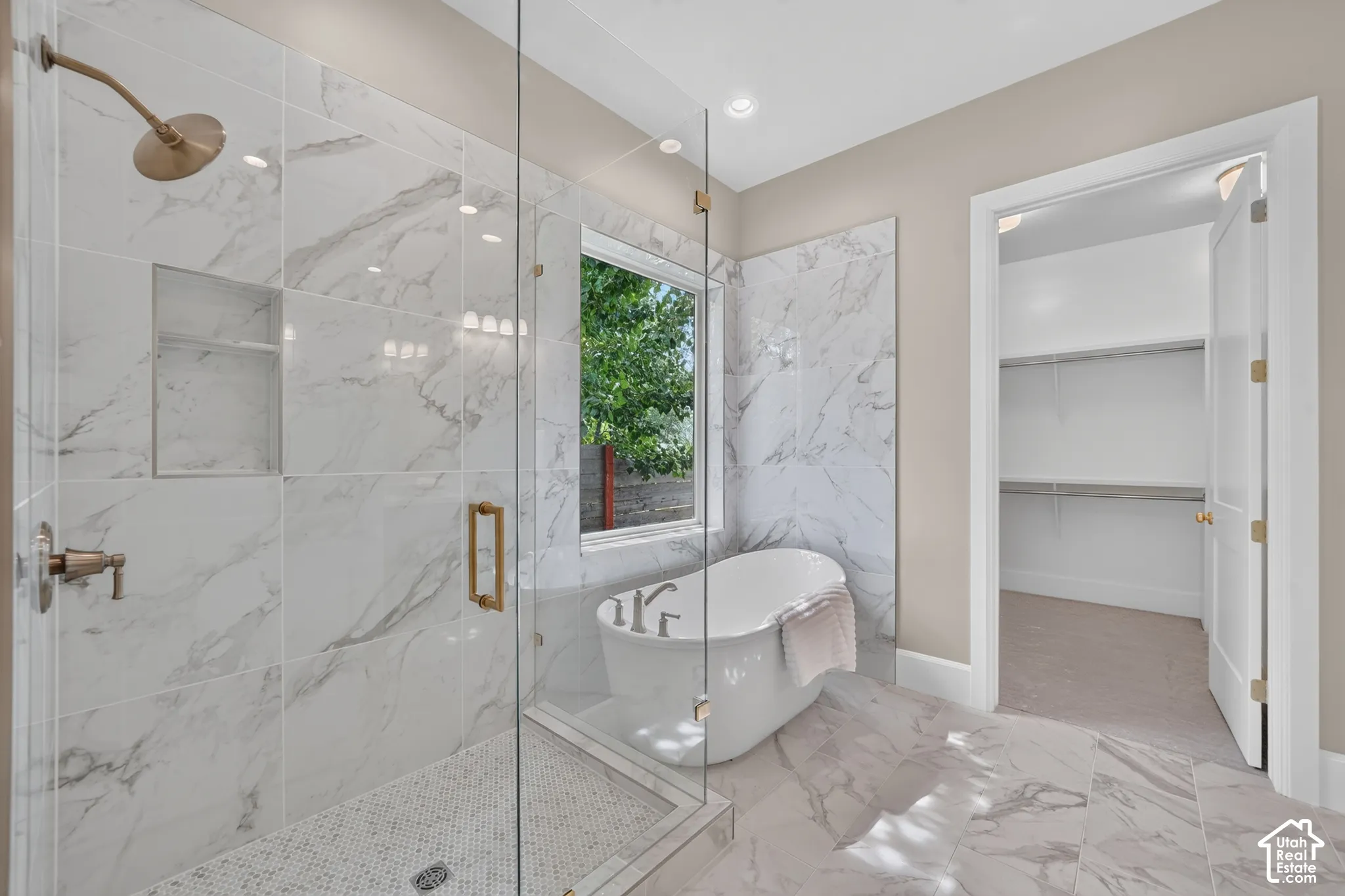 Spacious bathroom featuring a freestanding tub, glass-enclosed shower with a built-in niche, and large format tile flooring