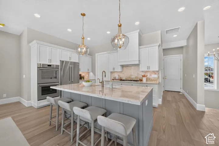 Open-concept kitchen with a central island, recessed lighting, double wall ovens, and wood-finish flooring