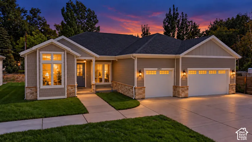 Modern exterior featuring horizontal siding, decorative stone accents, a dark shingle roof, a two-car garage with carriage-style doors, and an inviting entryway with a covered porch