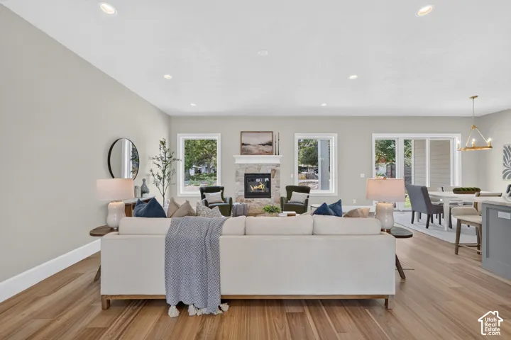 Recessed ceiling lighting, wood-finish flooring, stone-faced fireplace, multiple windows, and sliding glass doors