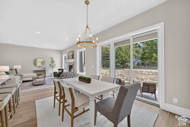 Open-concept dining area featuring a modern chandelier, wood-finish flooring, and expansive glass sliding doors
