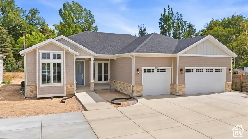 Contemporary ranch-style exterior with a dark shingle roof, neutral siding, and stone accents