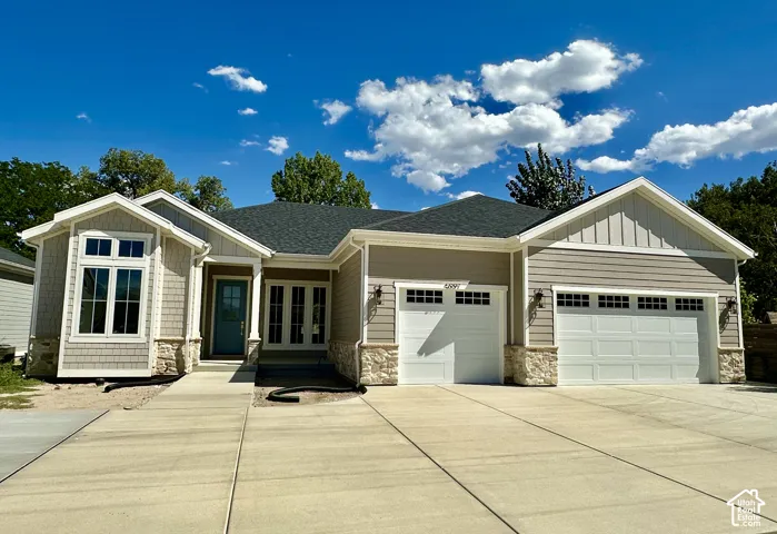 Single-story exterior with a mixed material façade, featuring a prominent bay window, a turquoise entry door, and two attached garage bays