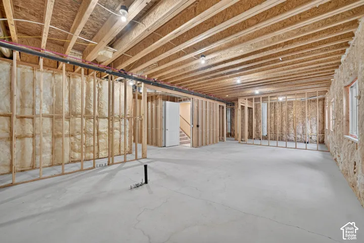 Unfinished basement with concrete flooring, exposed wood joists, and framed interior walls
