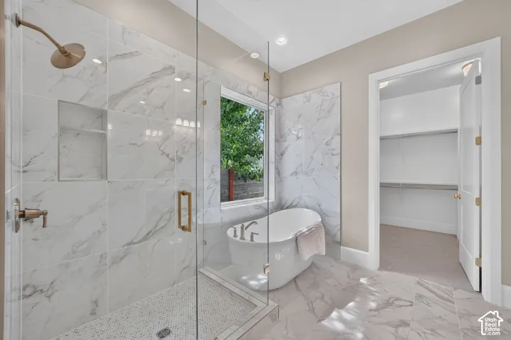 Spacious bathroom featuring a freestanding tub, glass-enclosed shower with a built-in niche, and large format tile flooring