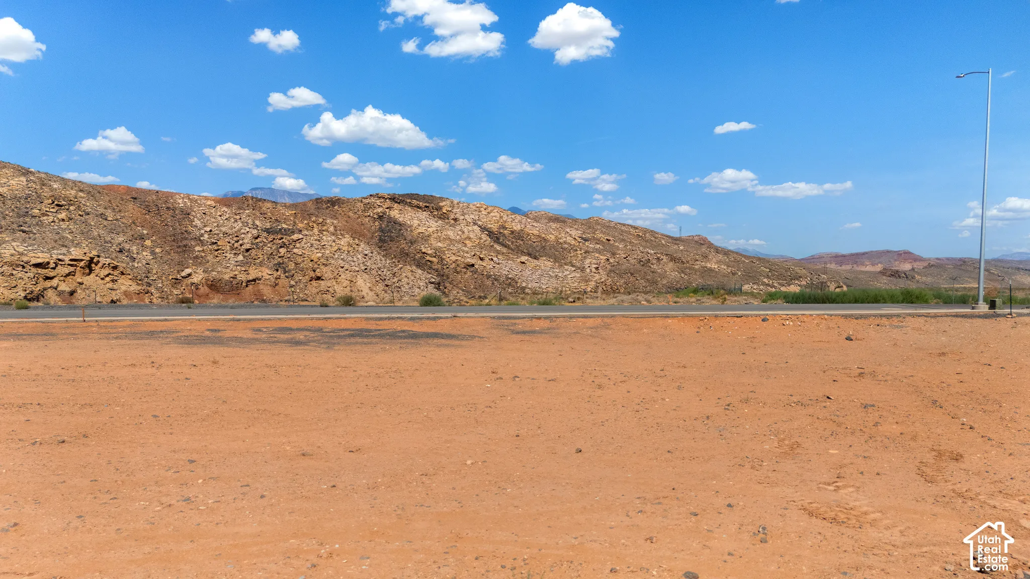 Expansive undeveloped desert terrain with distant rugged hills and a clear blue sky
