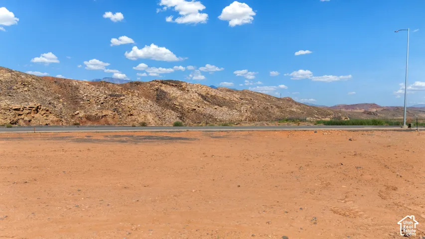 Expansive undeveloped desert terrain with distant rugged hills and a clear blue sky