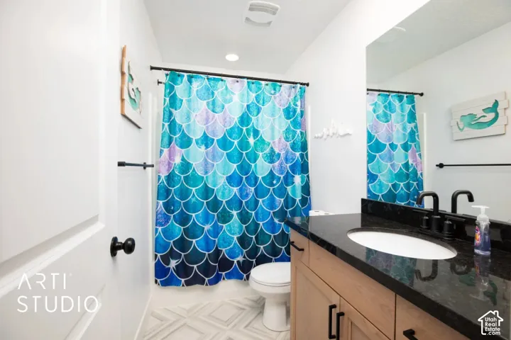 Bathroom featuring a vanity with a dark countertop, an undermount sink, and matte black fixtures