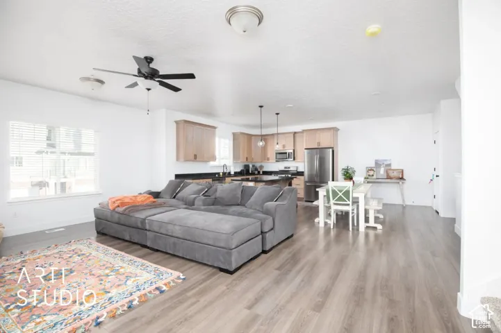 Open-concept living space featuring wood-finish flooring, recessed lighting, a modern ceiling fan, and a kitchen with stainless steel appliances
