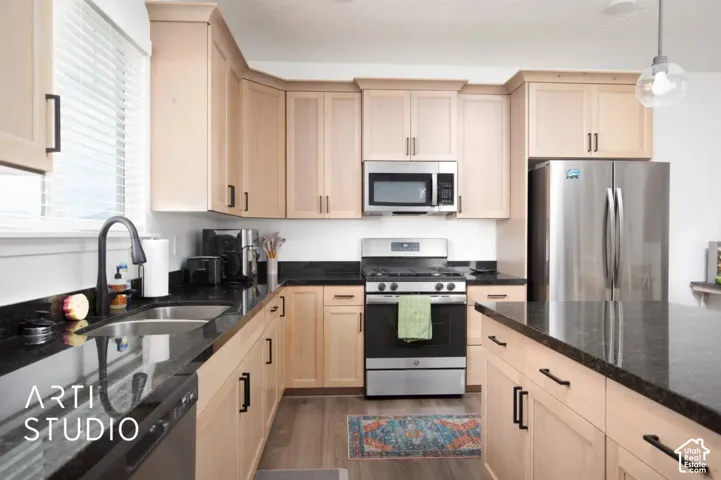 Well-appointed kitchen featuring light wood cabinetry, dark countertops, a stainless steel gas range, and a stainless steel French door refrigerator
