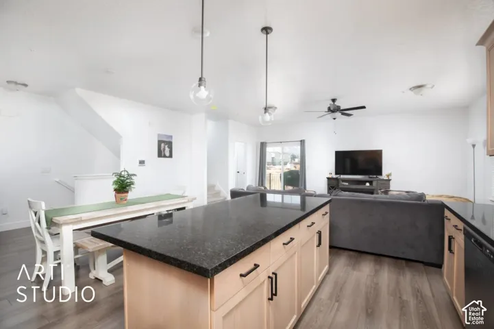 Kitchen island with dark countertop, light wood-finish cabinetry, and matte black hardware
