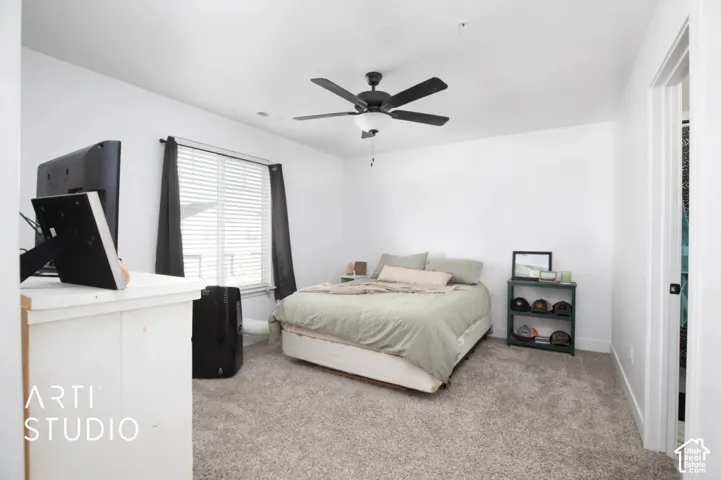 Carpeted bedroom featuring a ceiling fan with integrated lighting, a window with blinds, and white walls