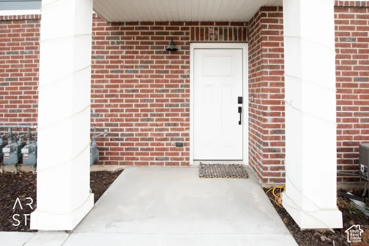 Brick facade with a white paneled entry door, concrete porch, and architectural columns