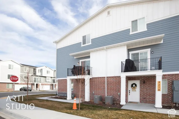 Exterior featuring brick and horizontal siding, with a white entry door and two upper-level balconies