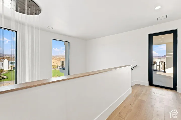 High ceilings with recessed lighting, large windows, wood-finish flooring, and a modern glass-paneled door leading to an exterior balcony
