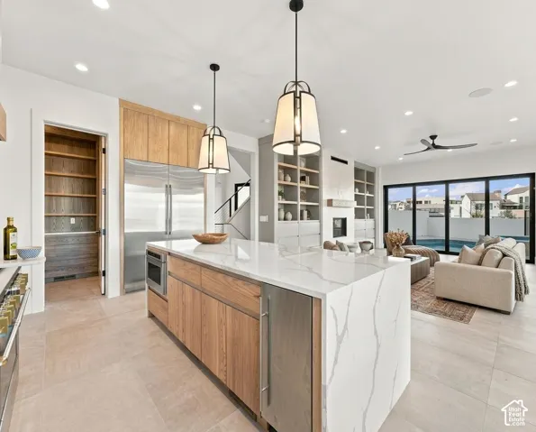 Expansive kitchen island with a waterfall countertop, stainless steel appliances, and wood-finish cabinetry