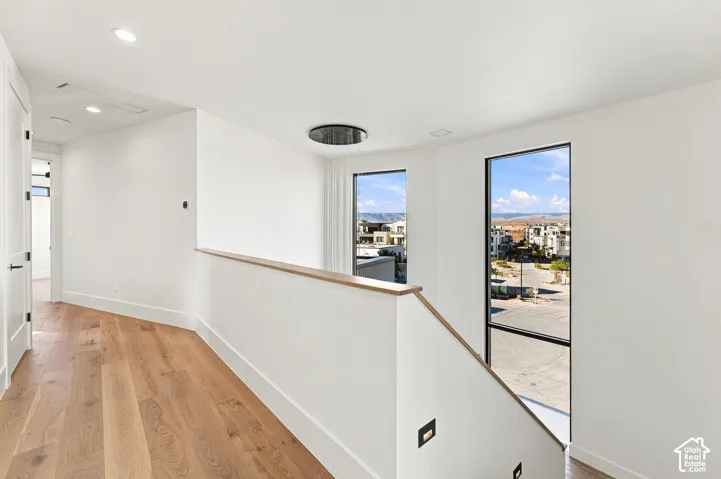 Wood-finish flooring, white walls, black frame windows, modern ceiling light fixture, and recessed lighting
