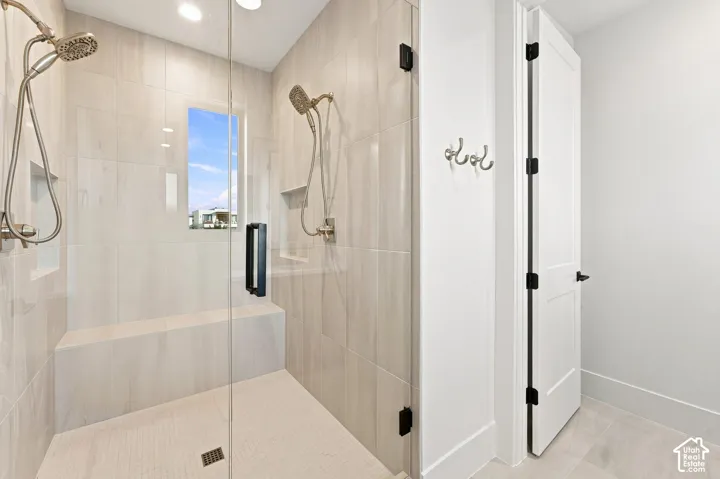 Glass-enclosed shower with a built-in bench, dual shower heads, and an integrated wall niche