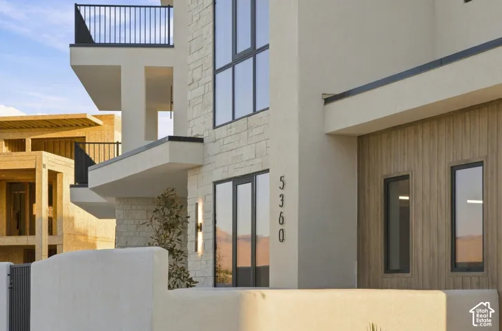 Stucco exterior with stone veneer accents, wood-finish paneling, and black-framed windows