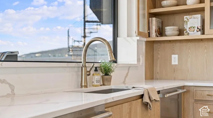 Integrated sink with a gooseneck faucet, light-toned cabinetry, and open shelving