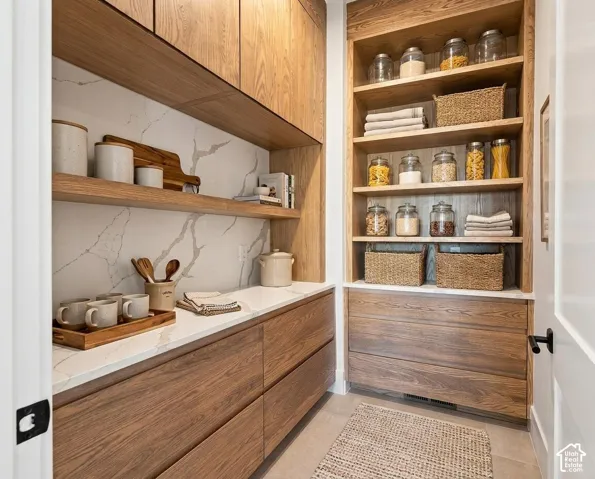 Wood-finish cabinetry and shelving with a white countertop and backsplash