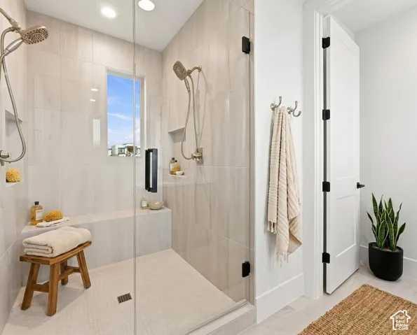 Frameless glass shower enclosure with dual showerheads, integrated tile bench, and a rectangular window