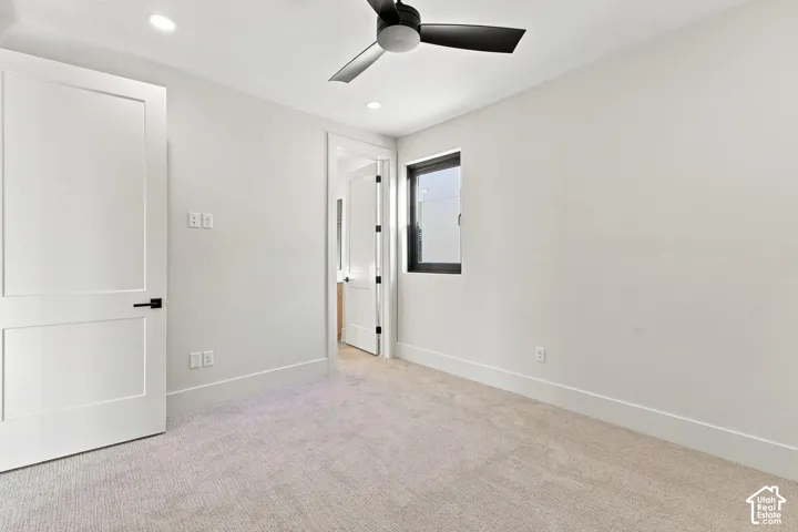 Neutral toned carpeting and walls, recessed lighting, and a ceiling fan