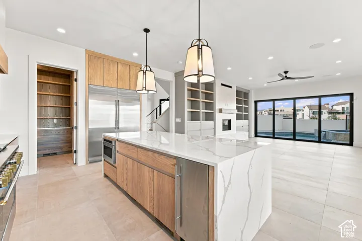 Gourmet kitchen with a waterfall island, stainless steel appliances, and wood-finish cabinetry