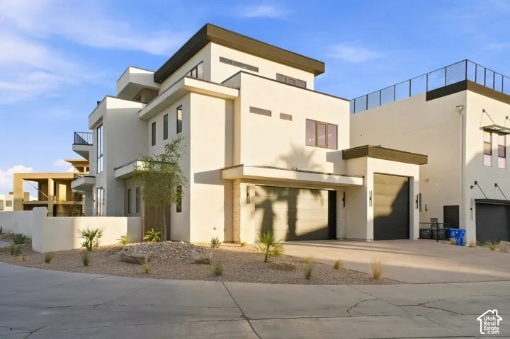 Contemporary exterior with white stucco finish, flat roofline, integrated two-car garage, and desert landscaping
