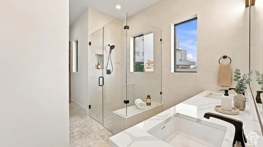Glass-enclosed shower with built-in bench, dual vanity with undermount sinks, and matte black fixtures