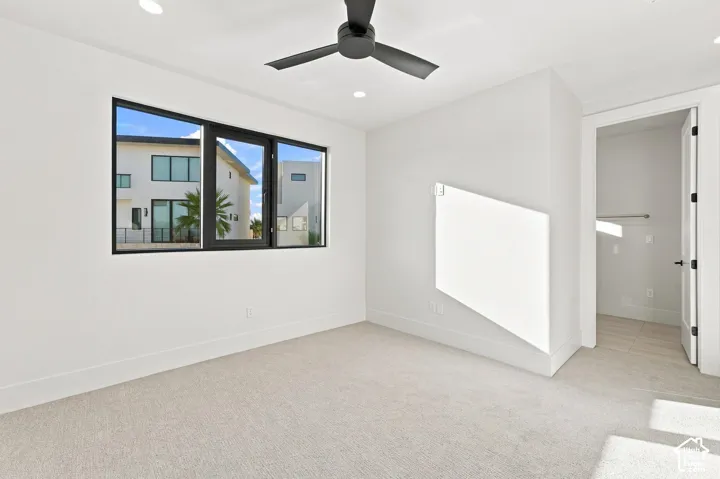 Recessed lighting, black ceiling fan, black-framed window, wall-mounted heating panel, and a closet with a built-in rod