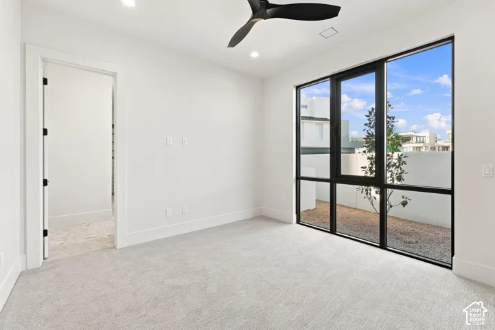 Recessed lighting, contemporary ceiling fan, expansive black-framed windows, and light-toned carpeting