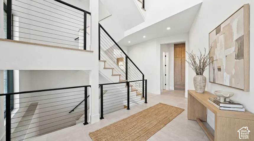 Spacious entryway featuring a cable railing staircase, recessed lighting, wood-finish flooring, and a paneled door