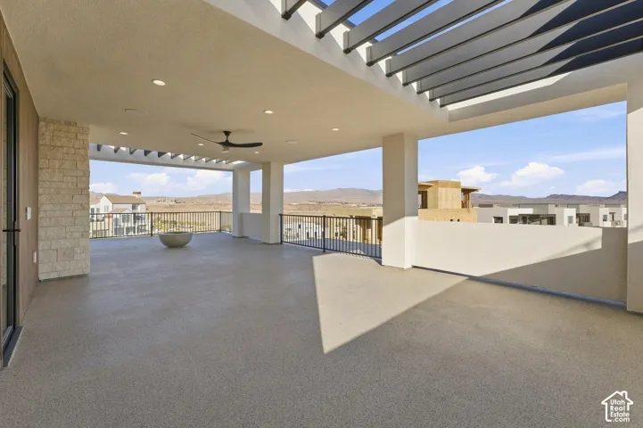 Expansive outdoor patio with a covered pergola, recessed lighting, and a ceiling fan