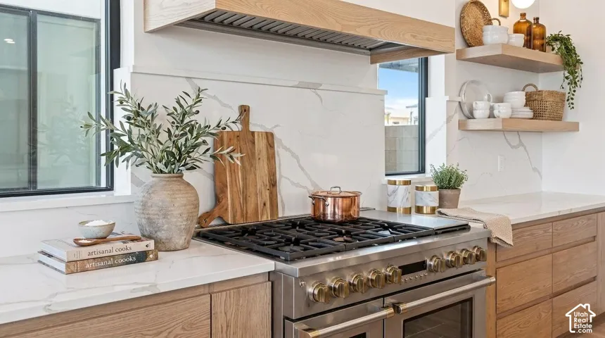 Stainless steel range with a wood-finish hood, quartz countertops, white tile backsplash, and wood-finish cabinetry
