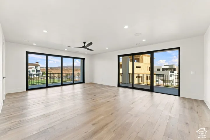 Expansive room featuring wood-finish flooring, two sets of large glass sliding doors, and recessed ceiling lighting