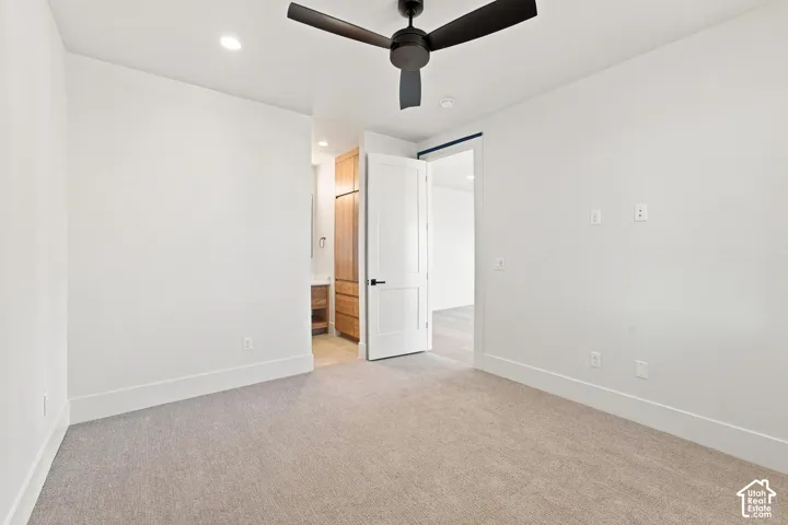Plush carpeting, recessed lighting, and a ceiling fan with matte black accents