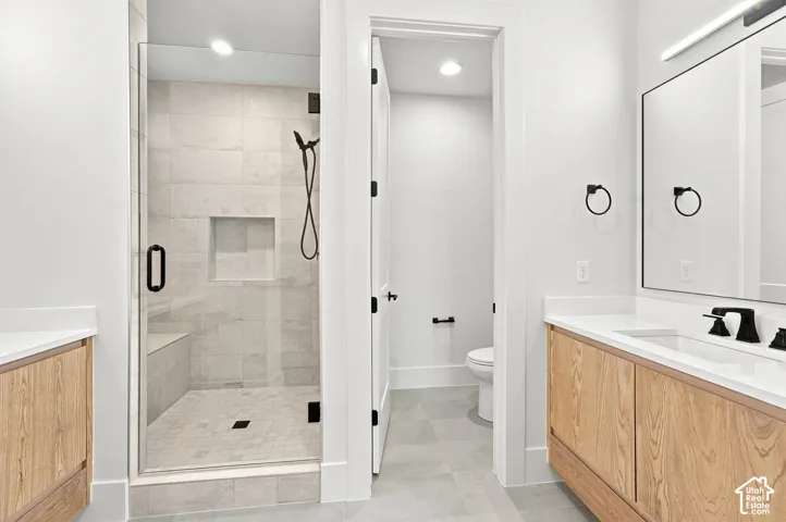 Frameless glass shower with a built-in bench and recessed niche, dual wood-finish vanities with undermount sinks and quartz countertops, and matte black fixtures throughout