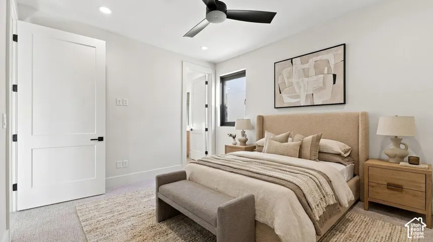 Recessed lighting illuminates a space featuring a ceiling fan with black blades, a single window, and a white two-panel door with black hardware