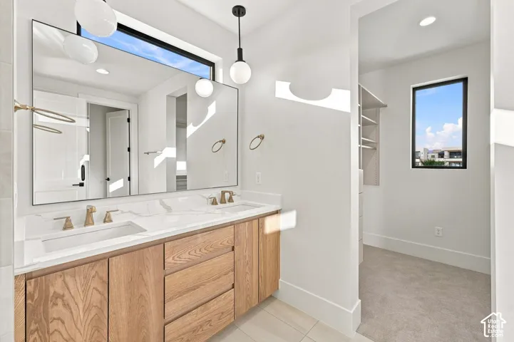 Dual vanity with wood-finish cabinetry, integrated sinks, and brass-tone fixtures