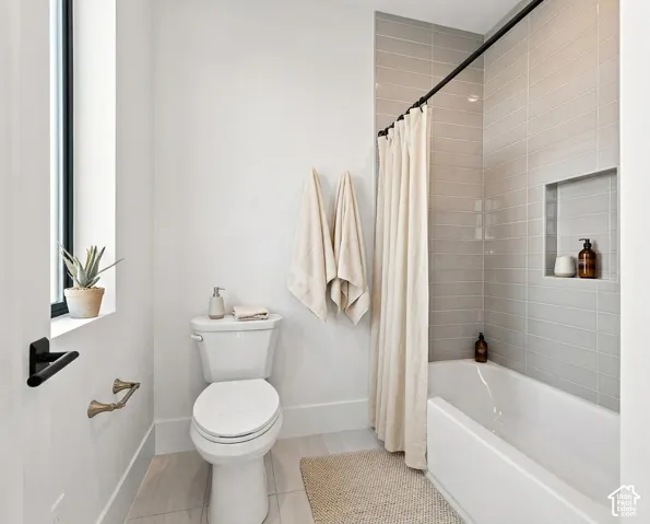 White subway tile surround with integrated shower niche, white bathtub, and floor-mounted toilet