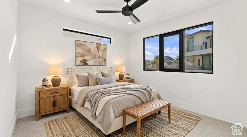 Recessed lighting, a modern ceiling fan, and large black-framed windows complement the light-toned walls